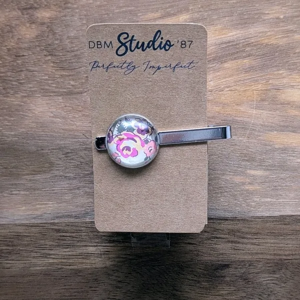 silver tie bar with pink, purple, yellow and green flowers on a white background